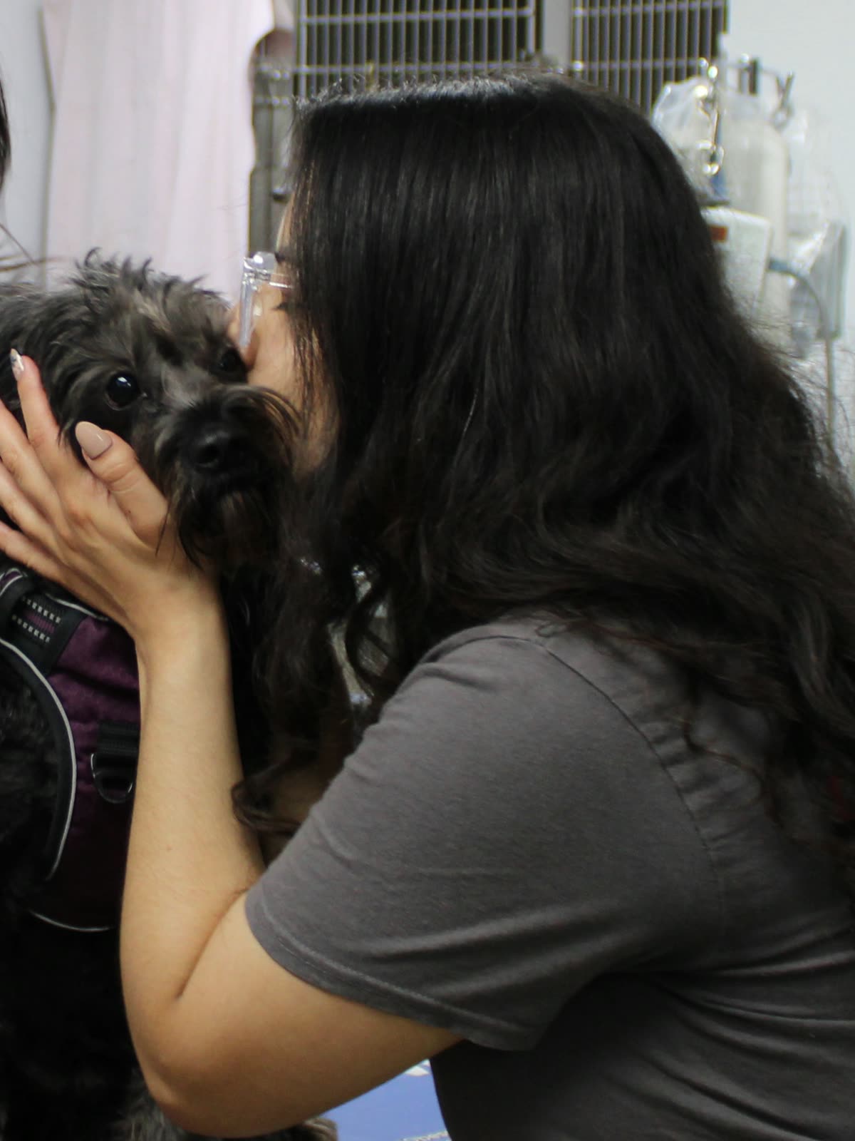 Clifton Ave Animal Hospital team member Amber kissing a small dark dog she is holding