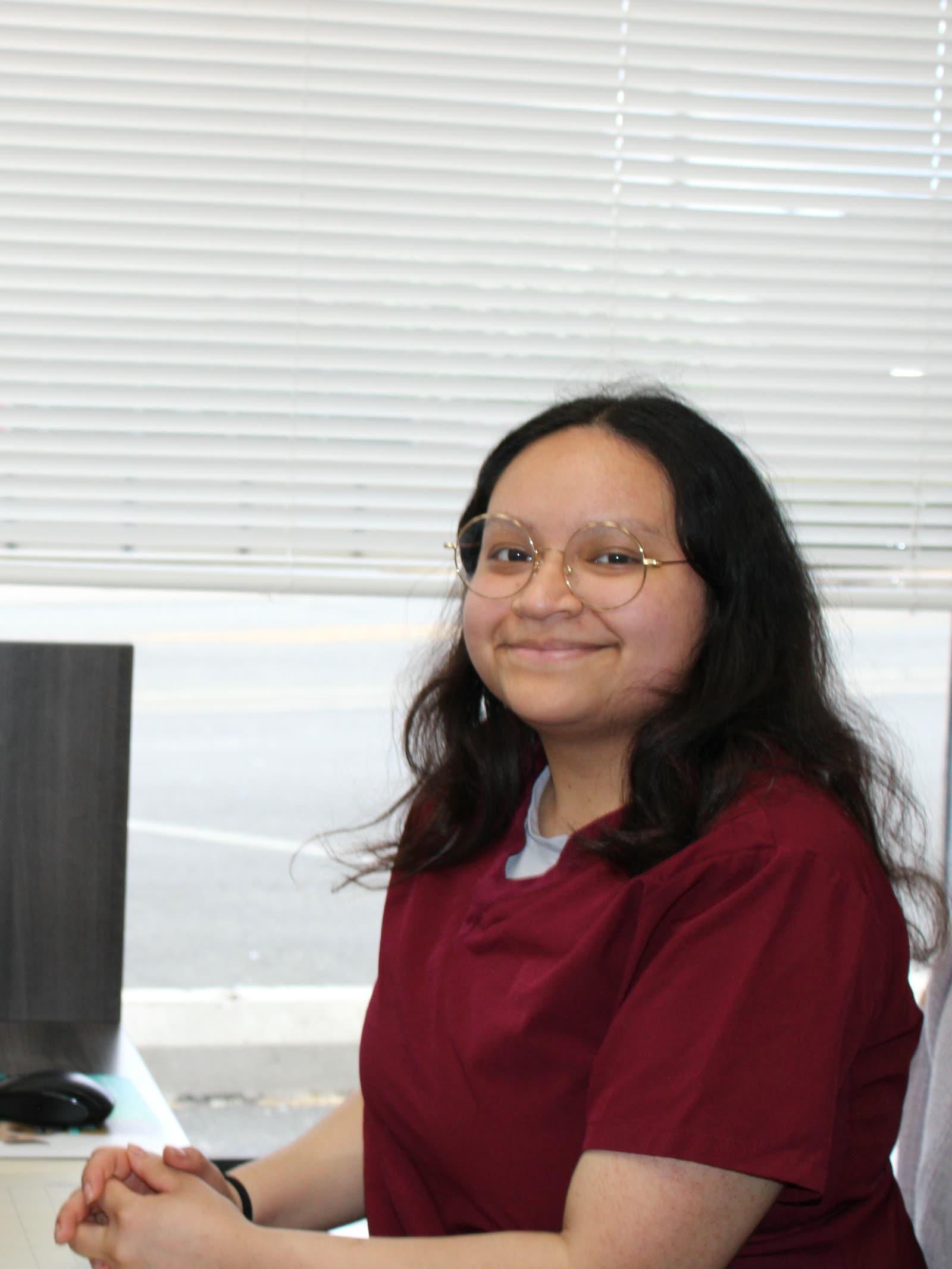 Clifton Ave Animal Hospital team member Carol smiling at the front desk in front of a sunlit window